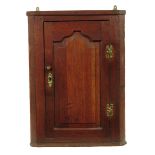 A George II oak hanging corner cupboard, with an arched fielded panel door enclosing two shelves,