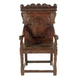 A 17th century and later oak panel back open armchair, the scroll carved toprail centred a male mask