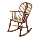 An early 19th century yew child's Windsor rocking chair, with a pierced splat back above an elm seat