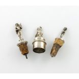 A small collection of three silver bottle stoppers, comprising: one modelled as a putto sitting on a