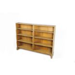 An oak double bookcase designed by Ernest Gimson, double width, four graduated shelves, on sleigh