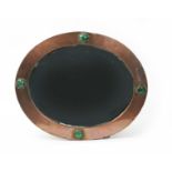 An Arts and Crafts patinated copper wall mirror probably retailed by Liberty & Co, oval section set