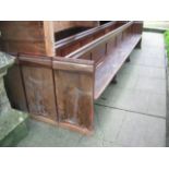 A pair of reclaimed stained pine and elm church pews with low panelled backs, chamfered slab ends