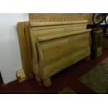 A stripped continental 5ft sleigh bed with shaped outline and heavy turned supports, complete with