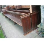 A pair of reclaimed stained pine and elm church pews with low panelled backs, chamfered slab ends