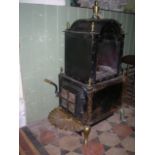 A floor standing stove of sheet steel construction, with riveted detail, domed top with brass urn