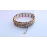 A Turkish silver gilt and enamelled bracelet, each shaped link highlighted with scrolling leaves