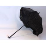 A late 19th/early 20th century lace and silk mourning parasol with black ground, ebonised handle