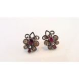 A pair of diamond and ruby earrings, each of scrolling floral form, set with two untested rubies,