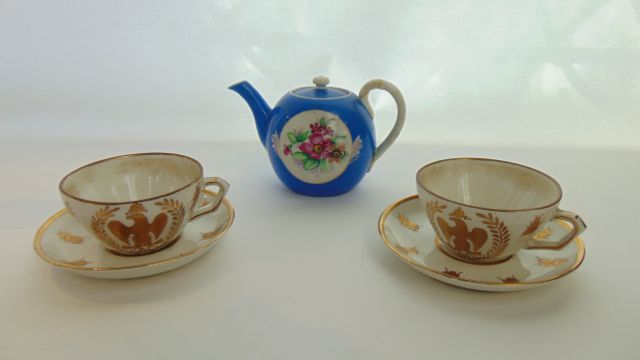 A pair of white ground continental tea cups and saucers with gilded bee decoration and eagle crest