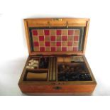 A 19th century pine games box, the hinged lid revealing a fitted interior accommodating a complete