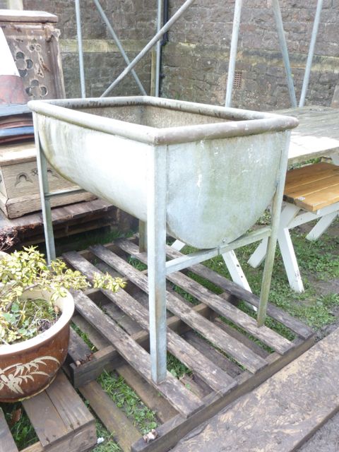 A galvanised steel freestanding water/feeding trough of rectangular form with horizontal half barrel