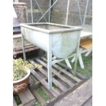 A galvanised steel freestanding water/feeding trough of rectangular form with horizontal half barrel