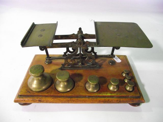 A late 19th/early 20th century assembly of postal scales, principally in brass raised on a timber