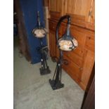 A pair of ironwork newel post lamps with shaped brackets and mottled glass shades encased with