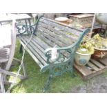 A Victorian style two seat garden bench with weathered timber slatted seat raised on a pair of