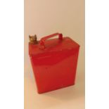 A vintage fuel can with all over red painted finish and impressed text reading Petroleum Spirit