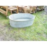 A galvanised tin bath of oval form with banded detail and screw cap drain hole