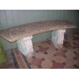 A weathered cast composition stone three sectional garden bench with crescent shaped slab seat