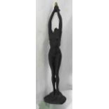A tall contemporary cast composition desk lamp in the form of standing female nude with both arms