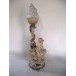 A heavy carved alabaster table lamp in the form of a seated female nude, holding flowers, perched