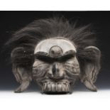 A substantial old Asian oversized hewn timber mask depicted with exaggerated ears and facial detail,