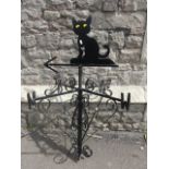An ironwork weather vane with simple scroll work detail and raised cat finial