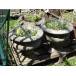 A set of three weathered cast composition stone campana shaped garden urns with square cut