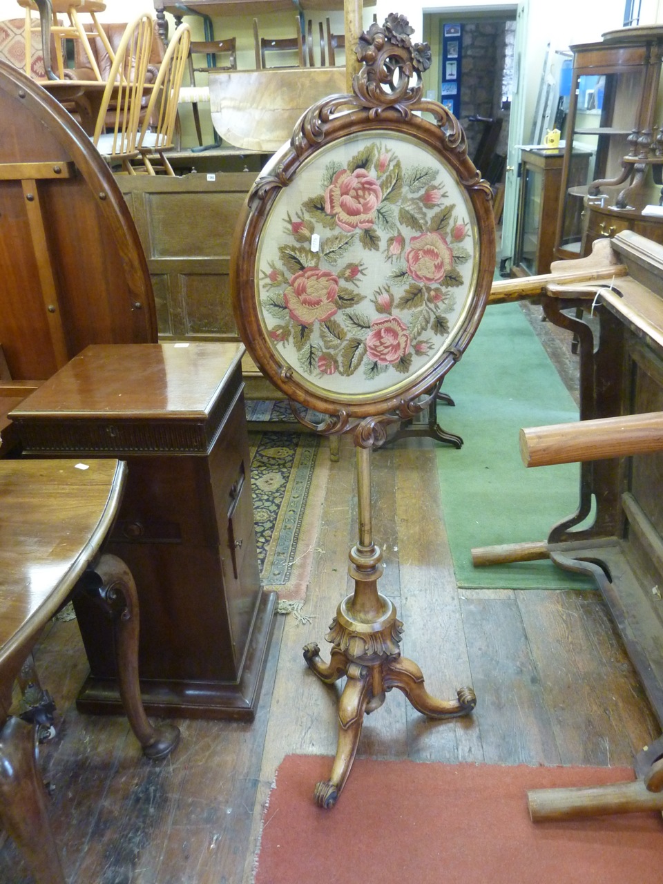 A Victorian walnut pole screen, the circular panel incorporating a drawn woolwork frieze of roses