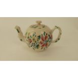 An 18th century salt glazed teapot of globular form with polychrome painted floral sprays and rustic
