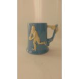 A 20th century Dartmouth pottery blue ground tankard with relief moulded detail of a rugby player on