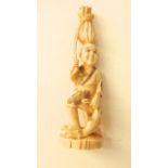 A 19th century ivory figure of a peasant holding a fish and with sack on his head
