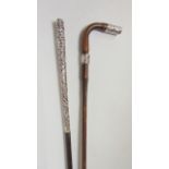 A slender walking cane with extensive embossed white metal handle, together with a further timber