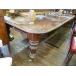 A Victorian mahogany extending dining table raised on four fluted supports fitted with three