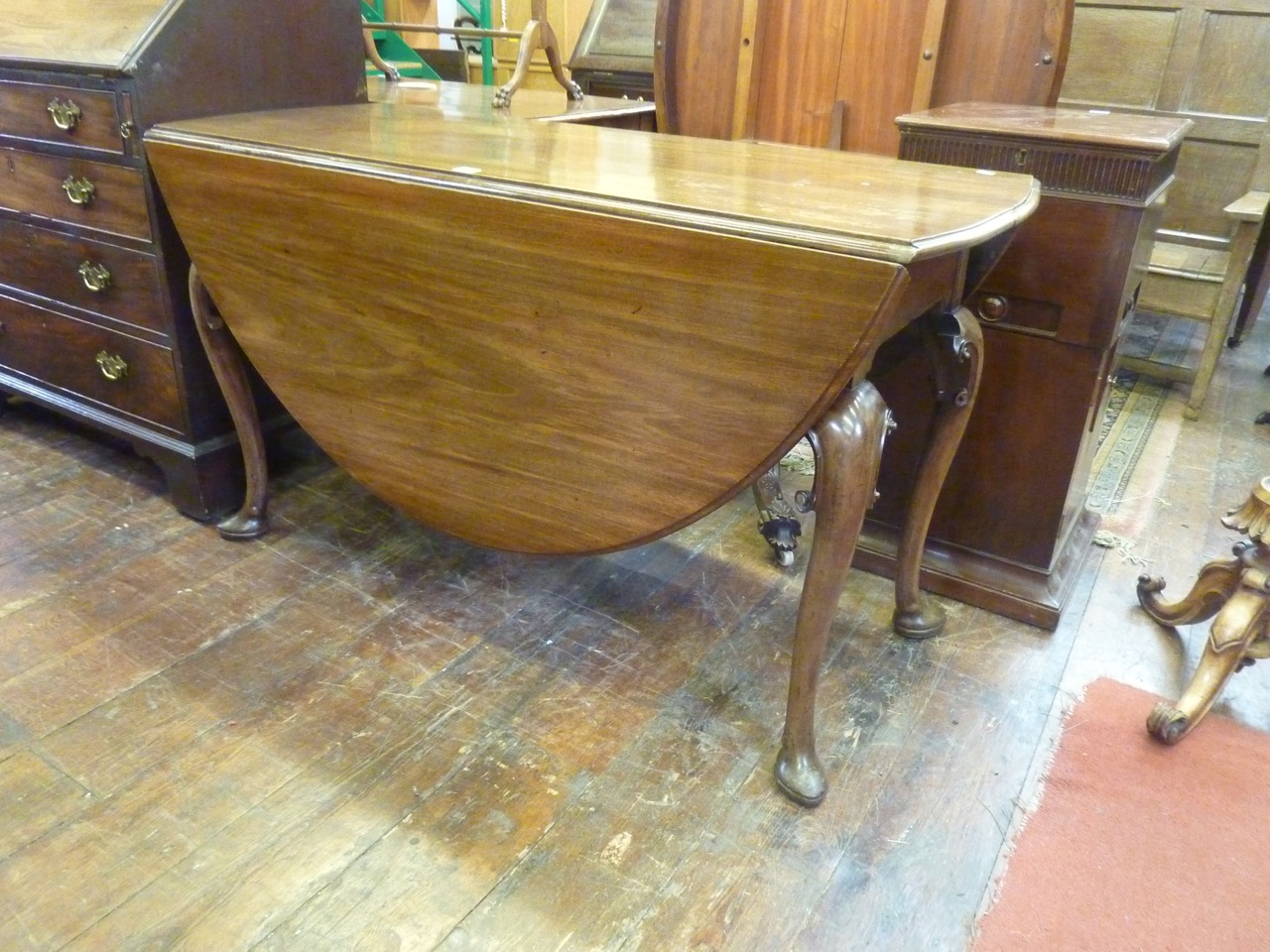 A Georgian mahogany pad foot dining table with pronounced supports with carved c-scroll knees