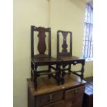 A similar pair of 18th century oak side chairs with vase shaped splats, plank seats, and raised on