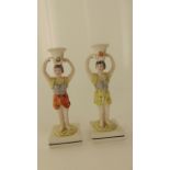 A matched pair of early 19th century candlesticks both in the form of boys in theatrical/classical