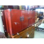 A Chinese crimson lacquered room divider enclosed by a series of hinged and sliding doors and with