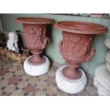 A pair of Regency cast iron campana shaped garden urns banded with classical figures, musicians