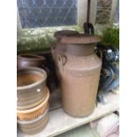 Two vintage cast iron milk churns complete with caps, with raised relief lettering advertising