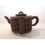 An oriental terracotta teapot of double skinned construction and of lobed form with moulded