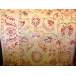 A substantial cream ground eastern style wool carpet with scrolling foliate and floral decoration in