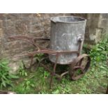 A vintage garden water barrow, the ironwork frame with spoke wheels supporting a removable