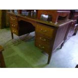 An oak pedestal desk fitted with six frieze drawers and raised on square tapered legs