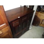 A reproduction oak side cupboard, partially enclosed by panelled doors over a fall front