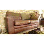 A contemporary tan leather upholstered two seat sofa with swept slab arms and loose cushions (The