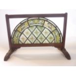 A leaded glass panel of arched form with hand painted trailing foliate border enclosing kite