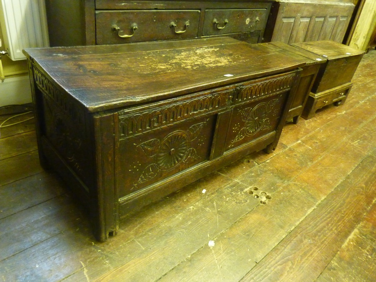 An 18th century oak coffer with hinged lid and panelled frame with moulded and carved detail, 110 cm