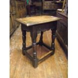 An antique oak joint stool with shaped apron and turned baluster supports united by stretchers