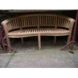 A contemporary teak 'banana' bench to be sold with the option of buying the matching following lot